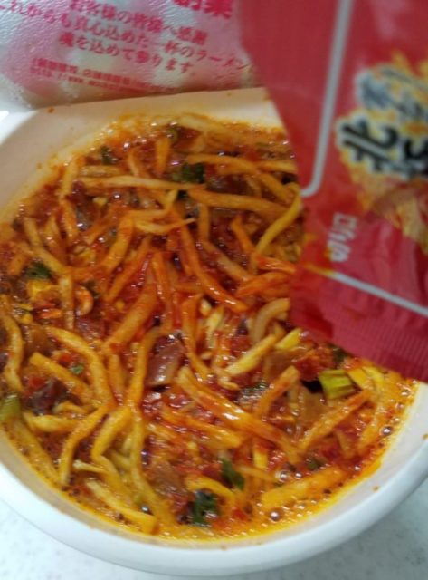 我慢ができないので4分半くらい経ったらふたを開けて、北極ラーメン専用の激辛オイルを注ぎます。